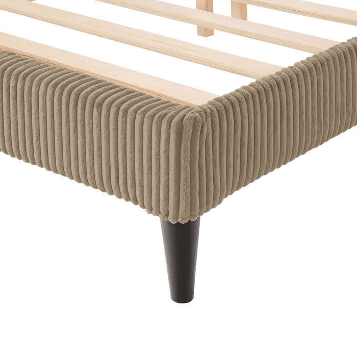 Left facing close up view of the footboard corner and leg of a modern light brown corduroy channel tufted headboard queen platform bed on a white background