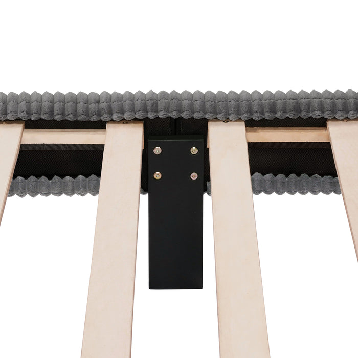 Front facing close up view of the interior support leg of a modern dark grey corduroy channel tufted headboard queen platform bed on a white background