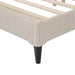 Left facing close up view of the footboard corner and leg of a modern ivory corduroy channel tufted headboard queen platform bed on a white background