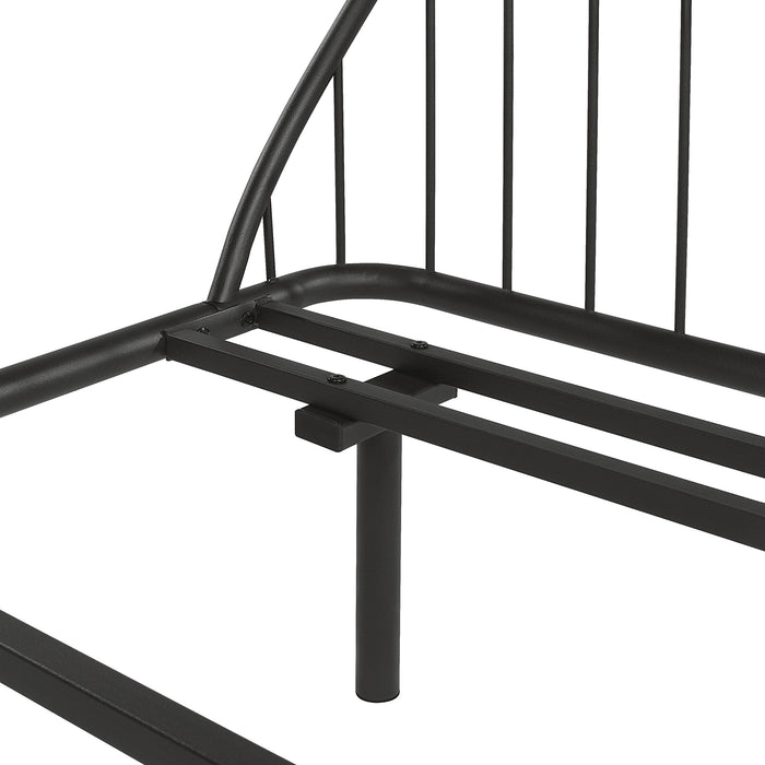 Left facing close up view of an industrial black metal full bed frame with rounded head and footboards on a white background