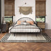 Front facing industrial black metal queen bed frame with rounded head and footboards in a room with linens and accessories