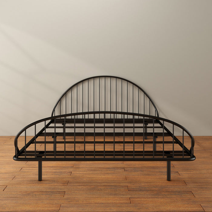 Front facing industrial black metal queen bed frame with rounded head and footboards in a room with a wood floor