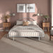 Front facing industrial white metal queen bed frame with rounded head and footboards in a room with linens and accessories