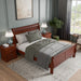 Right facing high-camera view of a three-piece traditional cherry finish solid wood queen bedroom set with (1) queen sleigh bed and (2) two-drawer nightstands in a room with linens and accessories