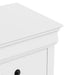 Right facing close up of a traditional white finish solid wood five-drawer chest showing its molded trim and tabletop, on a white background