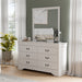 Left facing traditional white finish solid wood six-drawer dresser with a framed mirror in a room with accessories