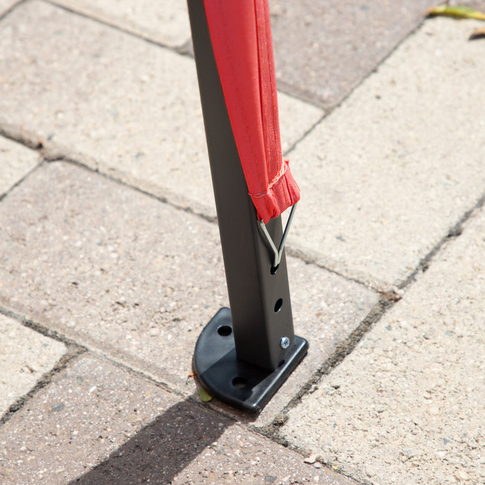 Close up view of the support leg of a modern red portable camping gazebo canopy with roof and anchors on patio paver stones