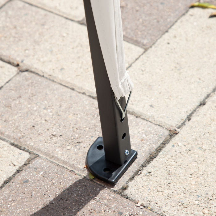 Close up view of the support leg of a modern white portable camping gazebo canopy with roof and anchors on patio paver stones