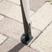 Close up view of the support leg of a modern white portable camping gazebo canopy with roof and anchors on patio paver stones