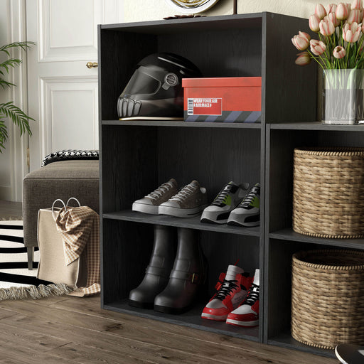 Left facing durable modern three-shelf black storage bookcase in a larger modular configuration in a room with accessories