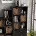 Right facing durable modern six-cubby black storage bookcase as part of a larger modular configuration in a room with accessories