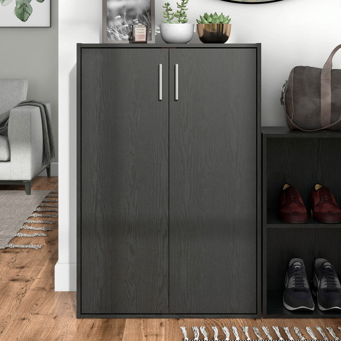 Front facing durable modern two-door black storage cabinet with silver handles as part of a larger modular configuration in a room with accessories