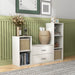 Right facing modern two-drawer white storage cabinet with silver handles in a larger modular bookcase with accessories