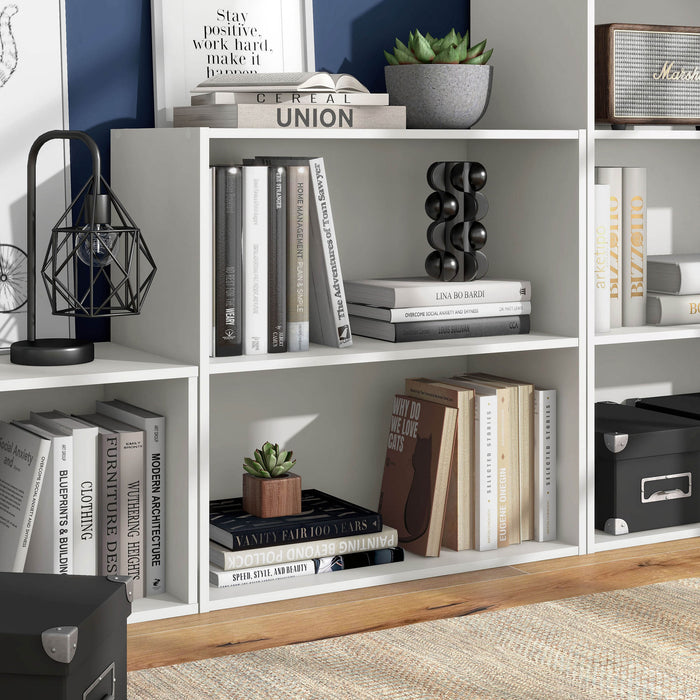 Right facing durable modern two-shelf white storage bookcase in a larger modular configuration in a room with accessories