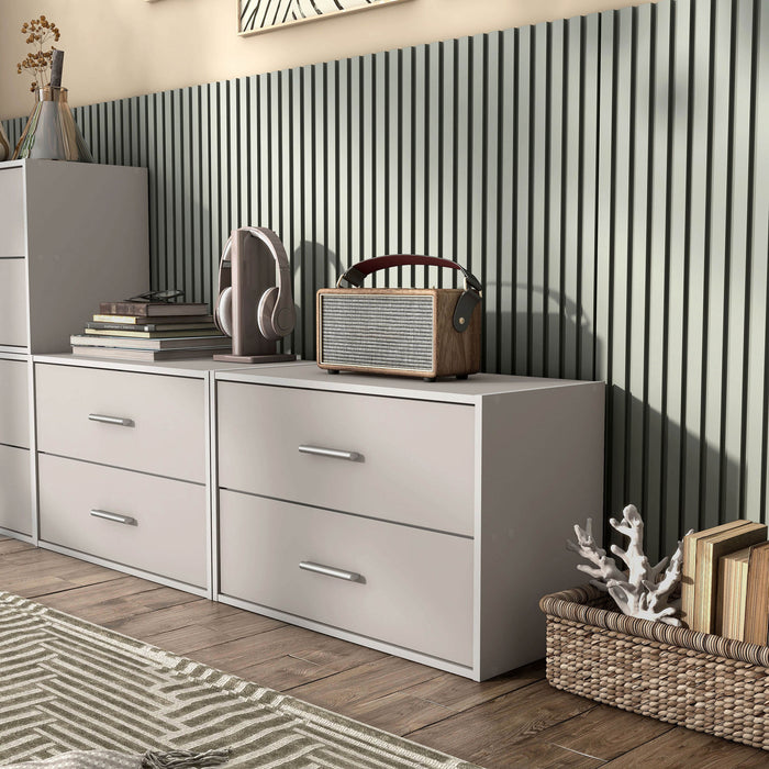 Left facing modern two-drawer taupe grey storage cabinet with silver handles in a larger modular bookcase with accessories