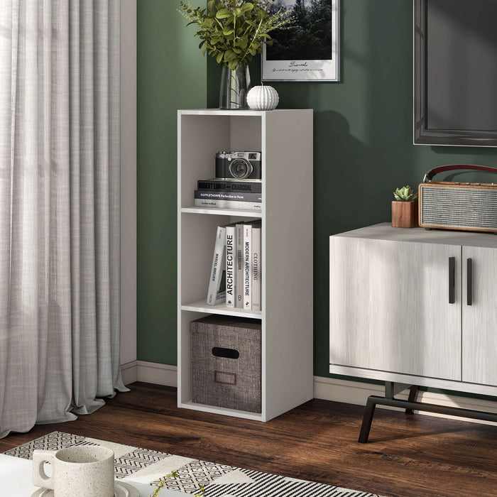 Left facing durable modern three-shelf slim taupe grey storage bookcase in a larger modular configuration in a room with accessories