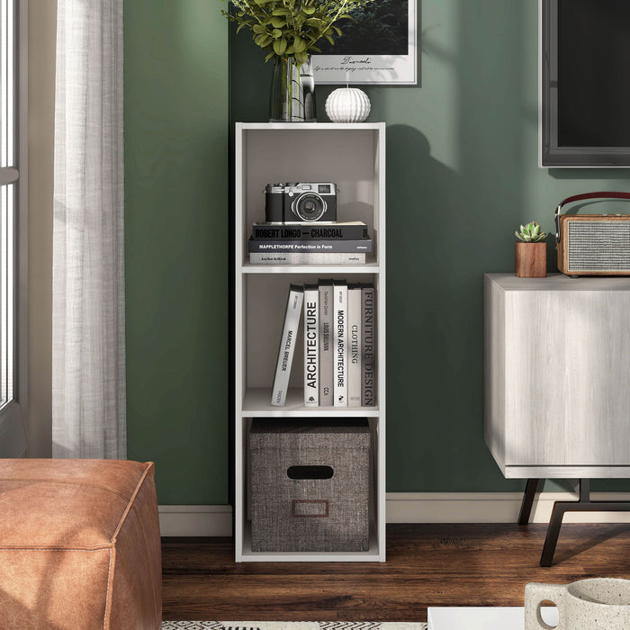 Front facing durable modern three-shelf slim taupe grey storage bookcase in a larger modular configuration in a room with accessories