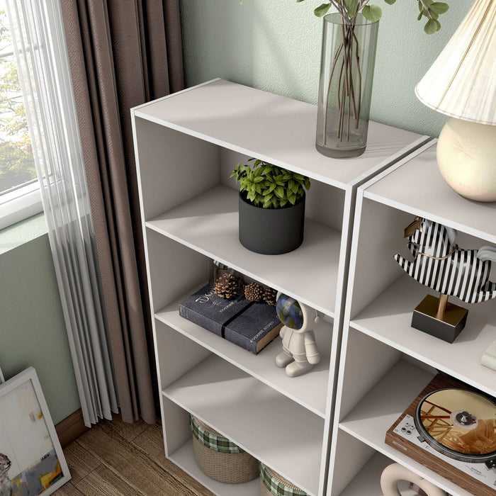 Left facing high-camera view of a durable modern four-shelf taupe grey storage bookcase in a larger modular configuration in a room with accessories