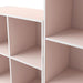 Close up view of a durable modern two-shelf light pink storage bookcase in a larger modular configuration on a white background