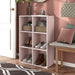 Left facing durable modern six-cubby light pink storage bookcase in a room with accessories