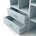 Left facing modern two-drawer light blue storage cabinet with silver handles and drawers open in a larger modular bookcase on a white background