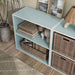 Left facing high-camera view of a durable modern two-shelf light blue storage bookcase in a larger modular configuration in a room with accessories