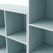 Close up view of a durable modern two-shelf light blue storage bookcase in a larger modular configuration on a white background