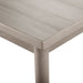 Left facing close up view of the corner and upper leg of a durable modern engineered wood rectangular dining table with a natural finish on a white background