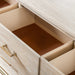 Left facing close up of open drawers on a transitional light oak seven-drawer dresser with a metal base, on a white background